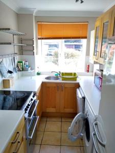 uma cozinha com um lavatório e uma máquina de lavar louça em 2 Bed Flat Near Station with Parking&Comgarden em Sutton