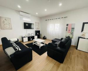 a living room with two black couches and a tv at Casa da Tapada in Torre de Moncorvo