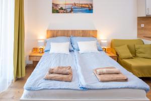 a large bed in a room with two towels on it at SWEET HOME Apartman, 30sqm studio, free private parking, mountain view, balcony, 20 min from downtown in Budapest