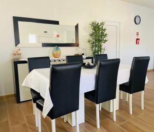 a dining room with a white table and black chairs at Casa da Tapada in Torre de Moncorvo