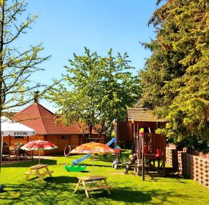einen Spielplatz mit Tischen und Sonnenschirmen im Hof in der Unterkunft Landhaus Levitzow in Levitzow