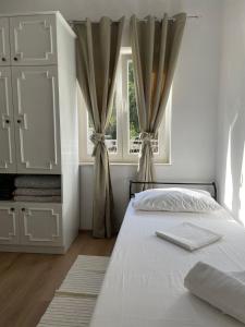 ein weißes Schlafzimmer mit einem Bett und einem Fenster in der Unterkunft Holiday house Fila in Turanj