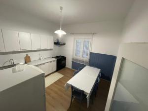 uma cozinha com armários brancos, uma mesa e um lavatório em Holiday house Fila em Turanj