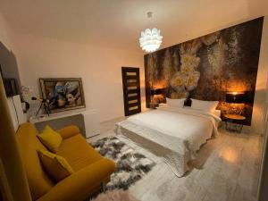 ein Schlafzimmer mit einem weißen Bett und einem gelben Sofa in der Unterkunft House of Art in Braşov
