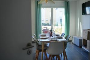 ein Esszimmer mit einem Tisch mit Stühlen und einem Fenster in der Unterkunft Douceur en Baie, maison neuve - 4 à 6 pers in Saint-Valery-sur-Somme