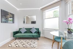 sala de estar con sofá verde y mesa en LuxLet Apartments - Heart of Hampstead, London en Londres