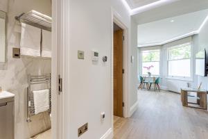 a white bathroom with a hallway with a table at LuxLet Apartments - Heart of Hampstead, London in London