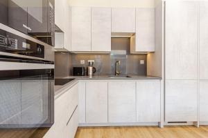una cocina con armarios blancos y fregadero en LuxLet Apartments - Heart of Hampstead, London, en Londres