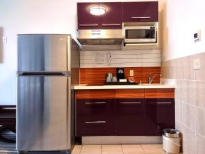 a kitchen with a stainless steel refrigerator and a microwave at Stars Inn and Suites - Hotel in Fort Saskatchewan