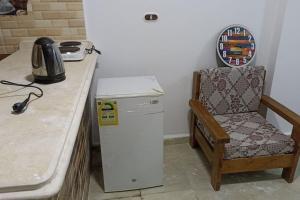 een keuken met een stoel en een kleine koelkast bij a lovely cozy flat by the sea in Alexandrië