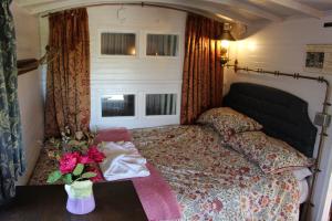 ein Schlafzimmer mit einem Bett und einer Vase mit Blumen auf dem Tisch in der Unterkunft The Edwardian Caravan 'Dora' in Lampeter