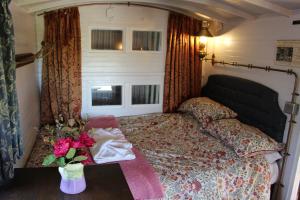 a bedroom with a bed and a vase with flowers on a table at The Edwardian Caravan 'Dora' in Lampeter
