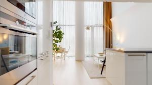 a kitchen with white cabinets and a dining room at Eurovea Apartments in Bratislava