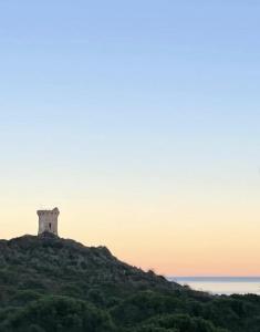 un phare au sommet d'une colline près de l'océan dans l'établissement Restaurant - Chambres d'Hôtes Terra Bella Lecci, à Porto-Vecchio