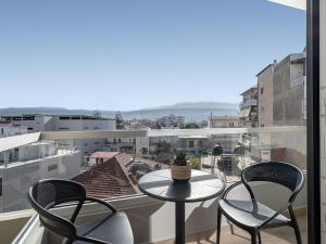 una mesa y sillas en un balcón con vistas en M City Hotel, en La Canea
