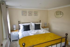 a bedroom with a large bed with yellow sheets and pillows at Cottage in Framlingham in Framlingham