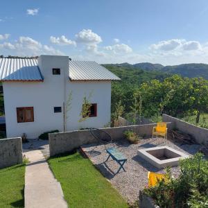 a backyard with a house and a bench and a chair at Casa Bouganville in Monte das Gameleiras