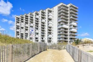 a tall white apartment building on the beach with a fence at Ocean Front Sea Terrace 209 Heated Pool in Ocean City