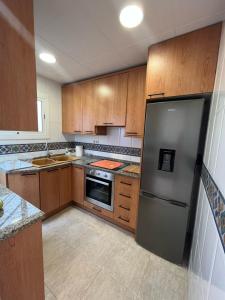 La cuisine est équipée d'armoires en bois et d'un réfrigérateur en acier inoxydable. dans l'établissement Apartamento St Zenon, à Arenys de Mar