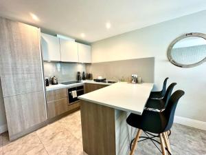 a kitchen with a counter and some chairs in it at Stunning 2 bedroom Apartment inc Free Parking - 1 Minute walk to Poole Quay - Great Location - Free Parking - Fast WiFi - Smart TV - Newly decorated - sleeps up to 4 - Close to Poole & Bournemouth & Sandbanks in Poole