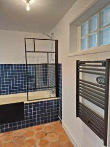 La salle de bains est pourvue d'une douche et d'un mur carrelé bleu. dans l'établissement Maison de vacances à la campagne, à Boisset