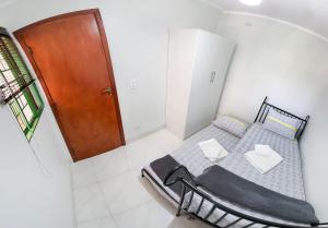 a small bedroom with a bed and a wooden door at Apto com Wi-Fi e churrasqueira em Campo Grande MS in Campo Grande