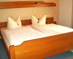 duże drewniane łóżko z białą pościelą i poduszkami w obiekcie Pension Katharina w mieście Seeboden