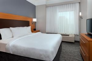 a hotel room with a bed and a flat screen tv at TownePlace Suites Buffalo Airport in Cheektowaga