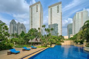 a pool in a city with tall buildings at The Ritz-Carlton Jakarta, Pacific Place in Jakarta