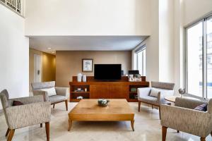 uma sala de estar com uma televisão, cadeiras e uma mesa em Marriott Executive Apartments Sao Paulo em São Paulo