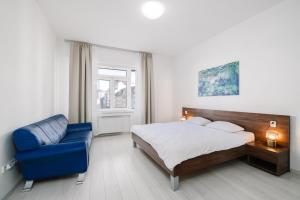 a bedroom with a bed and a blue chair at Self check-in apartments by Amber in Bratislava