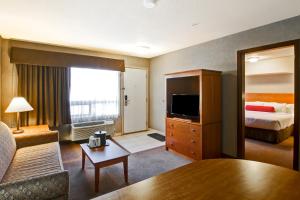 a hotel room with a bed and a living room at Ramada by Wyndham Ponoka in Ponoka
