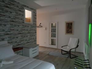 a bedroom with a brick wall with a bed and a chair at AL-Odeceixe Verde in Odeceixe