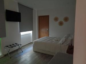 a bedroom with a bed and a television on the wall at AL-Odeceixe Verde in Odeceixe