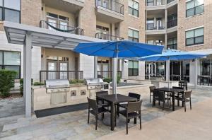 a patio with two tables and a grill with blue umbrellas at NEW! Modern & Spacious 1Br/1Bth in Central ATX! Close To Austin Hotspots! in Austin