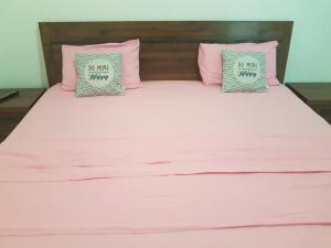 Una cama con almohadas rosas y grises. en RESIDENCE VERO, en Matoury