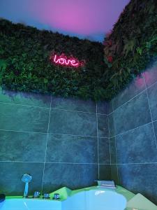 a sign that says love on the wall of a bathroom at LoveroomXspa in Bourg-Saint-Christophe