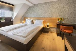 ein Schlafzimmer mit einem großen Bett und einem Schreibtisch mit einem Stuhl in der Unterkunft Jauch's Löwen Hotel-Restaurant in Neuershausen