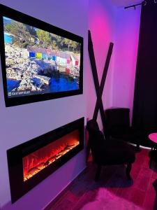 ein Wohnzimmer mit einem TV und einem Kamin in der Unterkunft LoveroomXspa in Bourg-Saint-Christophe
