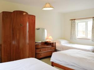 a bedroom with two beds and a dresser and a mirror at Beck Cottage in Ennerdale Bridge