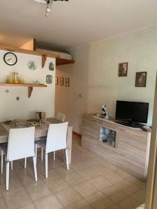 sala de estar con mesa, sillas y TV en Appartamento Albatros fronte spiaggia, en SantʼAlessio Siculo