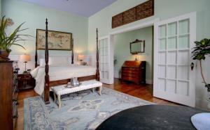 ein Schlafzimmer mit einem Himmelbett und einem Spiegel in der Unterkunft Forsyth Park Inn in Savannah