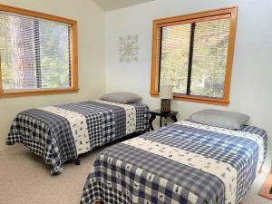two beds in a room with two windows at Mountain Cabin Retreat in the Pines in Prescott