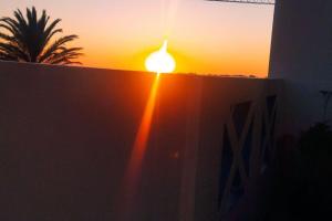 a sunset over a fence with a building and a tree at Lovers & Surfers Room - 5 min To Beach in Essaouira