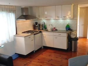a kitchen with white cabinets and a stove top oven at Heerlijk chalet op 5* camping in Tuitjenhorn