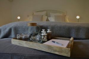 a wooden tray with bottles and glasses on a bed at The retreat in West Mersea