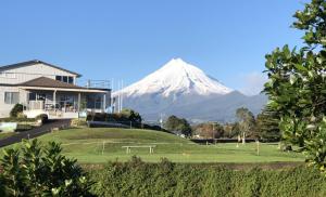 Im Hintergrund ein schneebedeckter Berg mit einem Haus und einem Feld in der Unterkunft Escape in New Plymouth + 20 Fotos