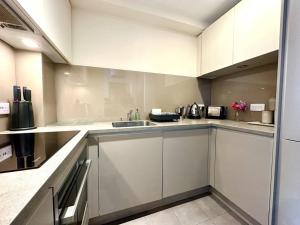 a kitchen with white cabinets and a sink at Beautiful Couples Retreat - FREE Parking & WiFi - 1 Minute walk to Poole Quay - Great Location - Free Parking - Fast WiFi - Smart TV - Newly decorated - sleeps up to 2! Close to Poole & Bournemouth & Sandbanks in Poole
