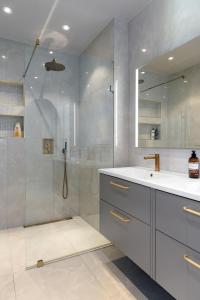 a bathroom with a shower and a sink and a mirror at Stylish and spacious family home in Stockholm