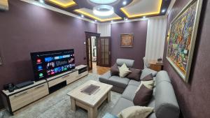 sala de estar con sofá y TV de pantalla plana en LUXURIOUS ACCOMMODATION IN 2BR APARTMENT, IN A SECURED AREA WITH COMFORTABLE DISTANCE TO R/W STATION, AIRPORT AND CITY CENTER. en Tashkent